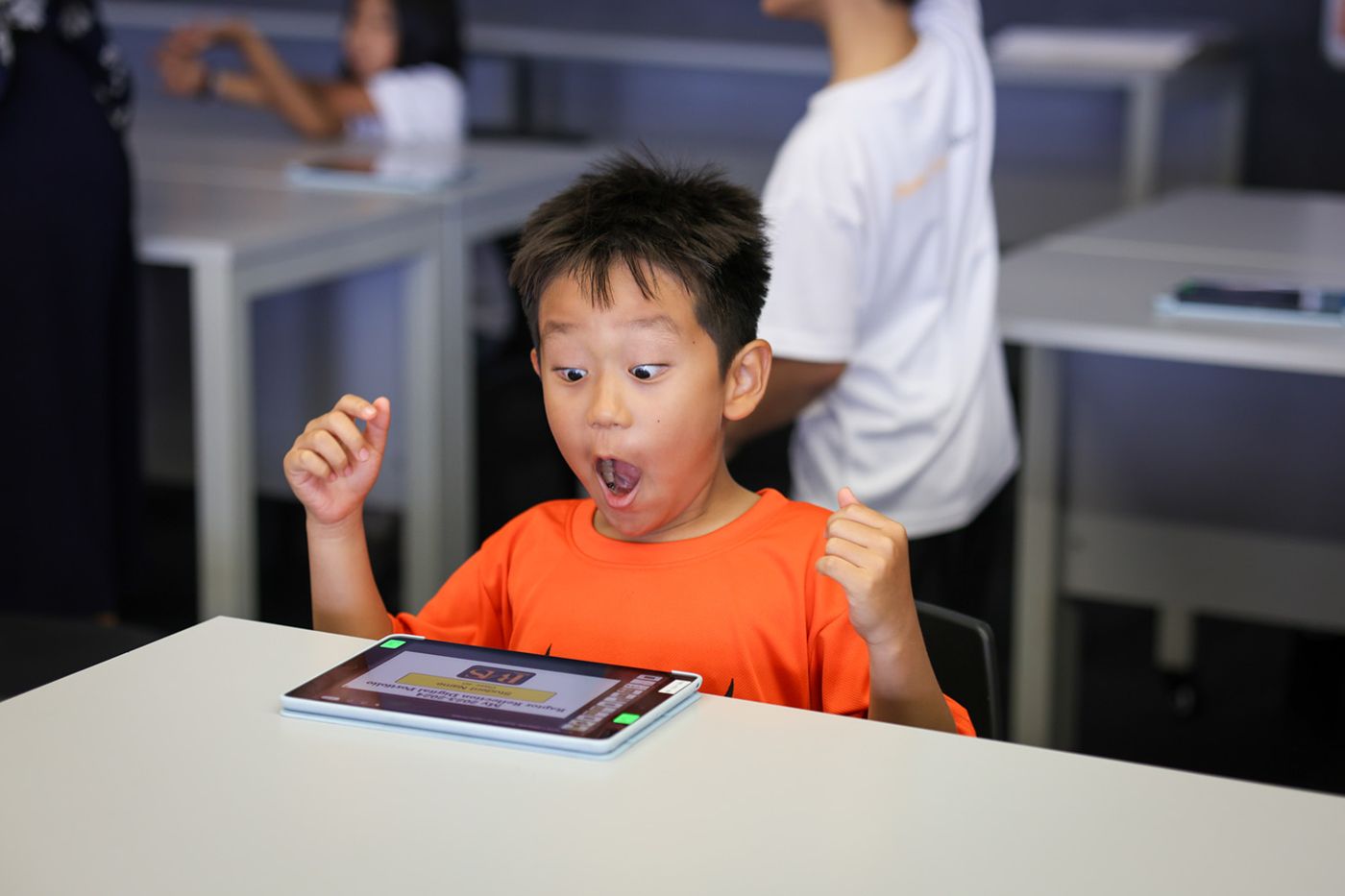 ラッフルズ・アメリカン・スクール: Child excited to learn on a tablet.